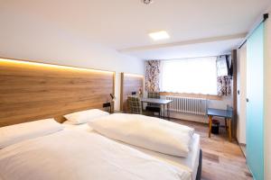 VöhrenbachGasthof Kreuz的卧室配有一张白色大床和一张书桌