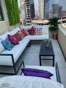 圣地亚哥Apartament Condo Amueblado, ENCOMENDEROS 200 El Golf, Las Condes Santiago con vista al Costanera Center的阳台配有白色沙发以及色彩缤纷的枕头。