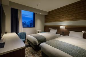 东京Shizutetsu Hotel Prezio Tokyo Tamachi的酒店客房设有两张床和窗户。