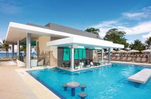 尼格瑞尔Riu Palace Tropical Bay - All Inclusive的一个带椅子的度假村游泳池和一间酒吧