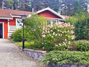 HargHoliday home VäTö的一座红色建筑和一些粉红色花卉的房子