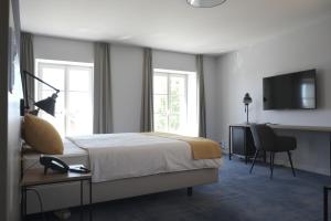 伯尼安Boutique Hôtel de l'Ecu Vaudois的一间卧室配有一张床、一张书桌和一台电视
