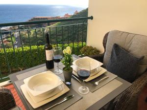卡尼索Oceanic Apartment的阳台上的桌子和两杯葡萄酒