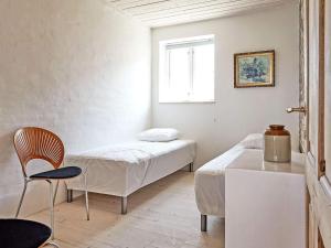 斯瓦讷克6 person holiday home in Svaneke的客房设有两张床、一把椅子和窗户。