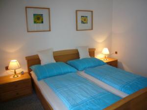 巴德哥依斯恩豪斯皮尔菲林公寓的一间卧室配有一张带蓝色床单的床和两盏灯。