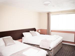 克鲁The Crewe Arms Hotel的客房设有两张床和窗户。