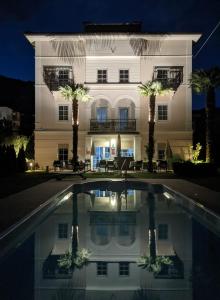 梅拉诺Garni Villa Tyrol - Adults Only的一座大型白色建筑,在游泳池前种有棕榈树