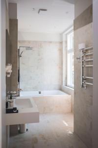 利耶帕亚Roze Boutique Hotel的白色的浴室设有浴缸和水槽。