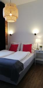 卢布林Rooms by Apartamenty Lubartowska Street的一间卧室配有一张带红色枕头的床和吊灯。