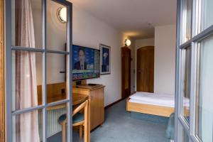 斯皮特安德劳Hotel Edlingerwirt - Sauna & Golfsimulator inklusive的客房设有一张床、一张书桌和电视