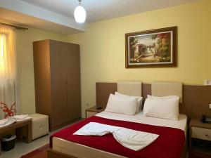 地拉那城市中心休闲酒店的卧室配有一张床,墙上挂有绘画作品