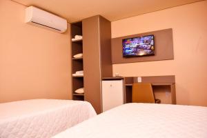 马卡帕Forte Express的一间卧室设有两张床,墙上配有电视。