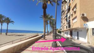 阿瓜杜尔塞Expoholidays - Apartamento en primera linea的海滨人行道,旁边是棕榈树海滩和一座建筑