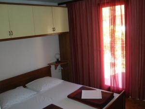 扎达尔波日克公寓酒店的一间卧室配有床和红色窗帘的窗户