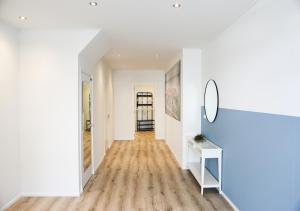 耶尔瑟克Prachtig appartement in het centrum van Yerseke的走廊设有白色墙壁、木地板和镜子