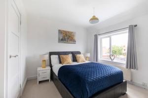 格洛斯特Modern Three Bedroom Home in Gloucester with Hot Tub的一间卧室设有蓝色的床和窗户。