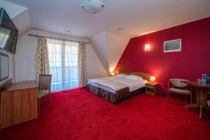 日基Pokoje w Oberży Czarny Groń的红色的房间,配有一张床和一张桌子及椅子