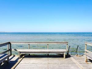 维斯比4 person holiday home in Visby的坐在靠近海洋的码头上的长凳
