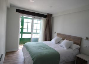 柯米拉斯Apartamentos El Muelle Comillas的一间卧室设有一张大床和大窗户