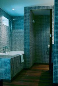 比亚里茨卡利娜旅馆的浴室设有浴缸和蓝色瓷砖淋浴。