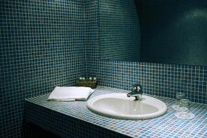 比亚里茨卡利娜旅馆的浴室配有水槽和蓝色瓷砖墙。