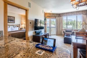 马姆莫斯湖Juniper Springs Lodge #413 - Luxury Ski in Ski out! 2 Bedroom的客厅设有一张床,台面上配有一台笔记本电脑