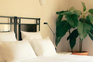 圣特罗佩Hotel la Ponche的一间卧室配有带白色枕头和植物的床