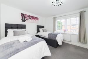 雷丁Greenfield Modern 3BR Home - Southcote lane , Reading的一间卧室设有两张床和窗户。