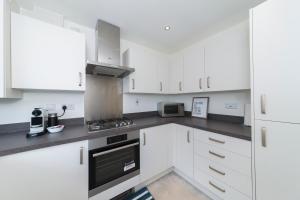雷丁Greenfield Modern 3BR Home - Southcote lane , Reading的厨房配有白色橱柜和炉灶烤箱。