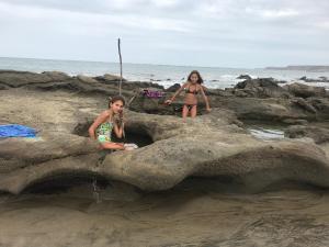 索里托斯竹苑酒店的两个女孩坐在沙滩上的岩石上