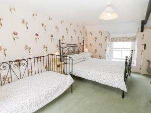 Hutton le HolePrimrose Hill Farmhouse的卧室内的两张床,墙上挂着鲜花