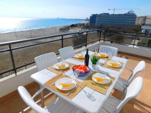 罗萨斯GMID IMMO Apartamento Oasis Atico的一张带白色椅子的桌子,享有海滩美景