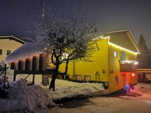 上罗伊特Ferienwohnung im Landhausstil的站在黄色房子前面的人,灯火通明