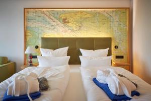 博尔库姆四季岛屿酒店的一间卧室配有两张带毛巾和地图的床。