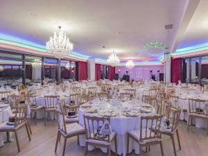 阿布兰特什Luna Hotel Turismo的宴会厅配有白色的桌椅和吊灯