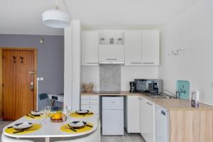 维勒班Nice studio with balcony and parking in Villeurbanne near Lyon - Welkeys的厨房配有白色橱柜和带黄色充电器的桌子