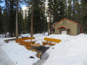 路易斯湖HI Mosquito Creek - Wilderness Hostel的雪上小屋前面设有长椅