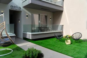 内亚卡瓦里Aelia Seaside Luxury Suites的房屋设有绿色庭院、椅子和阳台