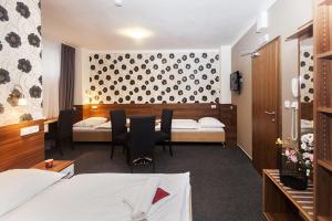 Bučovice阿卡达酒店的酒店客房带两张床和一张桌子以及椅子。