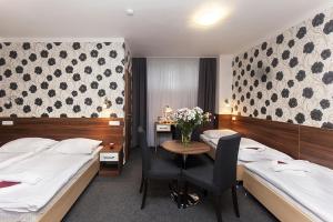 Bučovice阿卡达酒店的酒店客房,设有两张床和一张鲜花桌。