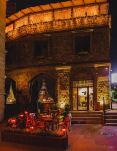 巴库Maajid Hotel & Restaurant的一座石头建筑,前面有坐在桌子上的人