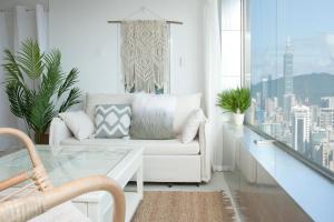 台北所在行旅-小所在 urban abode apartments的客厅配有白色沙发和玻璃桌