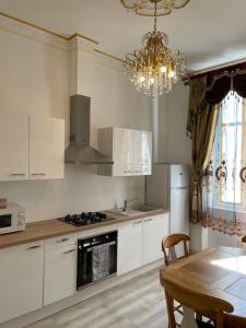 纳博讷Studio familial Maison de L'église du Couvent的厨房配有白色橱柜、桌子和吊灯。