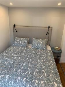 卢恩斯基尔Nyrenoverat källarlägenhet的一张带蓝色和白色棉被的床和两个枕头