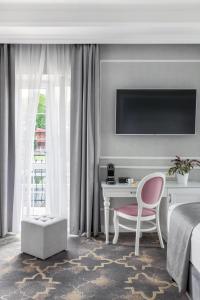 克拉科夫Merci Boutique Hotel的酒店客房设有一张床、一张书桌和一台电视机。