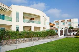 查察拉卡斯Artisan Family Hotels and Resort Collection Playa Esmeralda的白色的建筑,有石墙和草