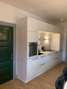 斯卡恩Ferie lejlighed i Skagen -huset med den grønne dør的厨房配有白色橱柜和微波炉