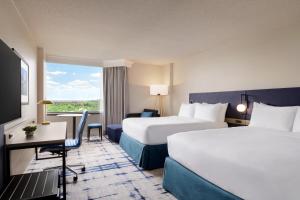 绿带城Crowne Plaza College Park - Washington DC的酒店客房设有两张床、一张书桌和一个窗户。