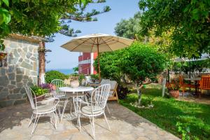 瓦西里科斯Alavastros Maisonettes Near 3 sandy beaches的庭院配有桌椅和遮阳伞。
