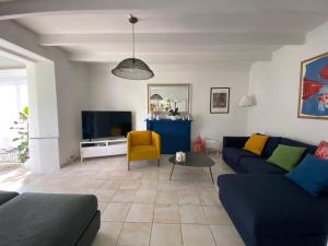 Clohars-FouesnantMaisons Les Gites de l'Odet的客厅配有蓝色的沙发和电视